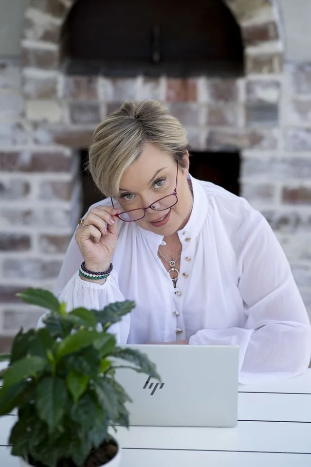 Catheryn Wright at her desk, glasses in hand