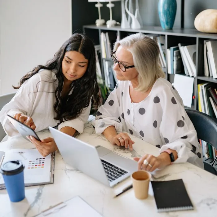 Mentor and business owner reviewing plans on a tablet and laptop